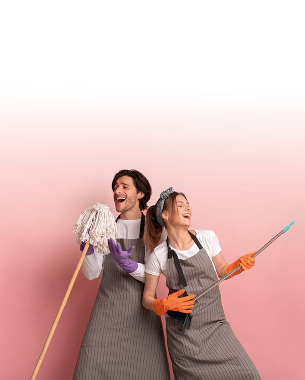 Millennial couple having fun while making spring cleaning, using broom like air guitar and singing into mop,