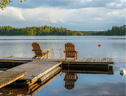 Two wooden chairs at Sunset on a pier on the shores of the calm Saimaa lakein Finland - 4