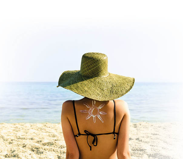 Woman on beach with sun symbol on her back - UV protection concept