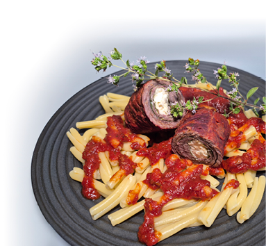 Das Bild zeigt ein k stlich angerichtetes Nudelgericht auf einem dunklen Teller. Auf den kurzen, gedrehten Nudeln (vermutlich Casarecce) liegt eine fruchtige, rote Tomatenso e. Obenauf liegen zwei aufgeschnittene Rinderrouladen, die mit einer cremigen F llung – vermutlich Frischk se oder Mozzarella – und Kr utern gef llt sind. Als Dekoration wurden frische Kr uterzweige, vermutlich Oregano oder Majoran, aufgelegt. Das Gericht wirkt herzhaft, mediterran und sehr appetitlich.