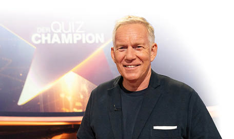 Der Quiz-Champion - Das Spenden-Special“: Johannes B. Kerner steht im Studio vor dem Sendungslogo und l chelt in die Kamera.