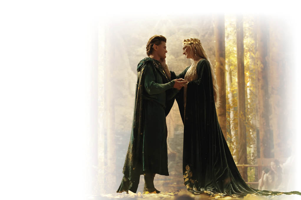 “Der Herr der Ringe: Die Ringe der Macht - Schatten der Vergangenheit": Elrond (Robert Aramayo) und Galadriel (Morfydd Clark) stehen sich in einem hell erleuchteten Wald gegen ber. Sie blicken sich an und halten sich an den H nden.