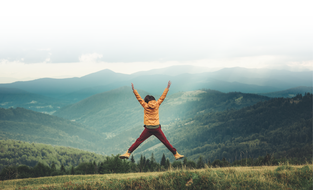 Joyful yougn woman jumping in the mountains while being impressed by beautiful scenary