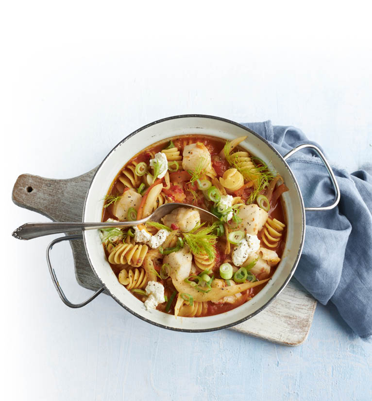 Topf mit Spiralnudeln, Gem se und Frischk se auf Holzbrett mit blauem Tuch