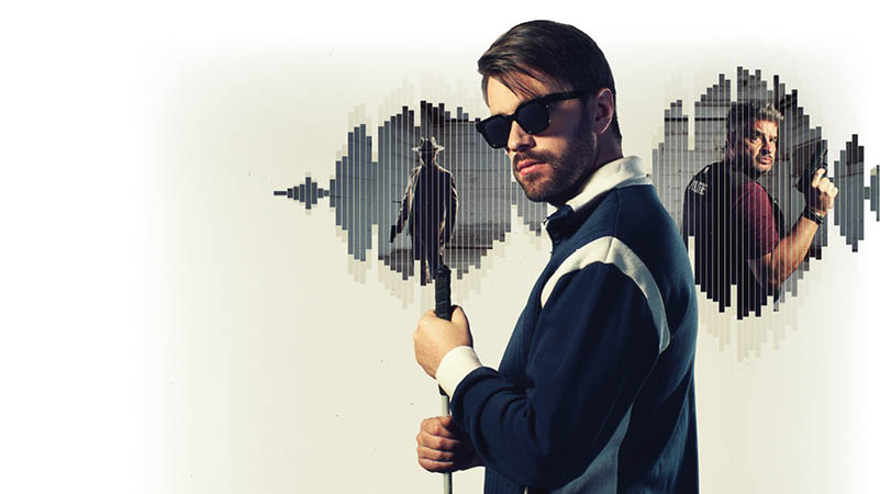 Das Bild zeigt einen jungen Mann im Vordergrund, der leicht seitlich zur Kamera steht. Er tr gt eine dunkle Sonnenbrille und ein sportliches Oberteil in dunklen Farben mit hellen Streifen. In der Hand h lt er ein Mikrofon, als w rde er singen oder sprechen. Sein Gesichtsausdruck wirkt konzentriert und selbstbewusst. Im Hintergrund sind zwei kreisf rmige, grafische Elemente zu sehen, die an Schallwellen oder Audiovisualisierungen erinnern. Innerhalb dieser Kreise erscheinen zwei weitere Szenen:  Links ist eine Person in einem Mantel, die von hinten zu sehen ist und durch eine eher leere, offene Umgebung geht.  Rechts ist ein Mann in Bewegung, der sich umdreht und etwas in der Hand h lt, als w re er in einer aktionsreichen Szene.  Die Farbgestaltung ist eher ged mpft, mit einem klaren Fokus auf den Mann im Vordergrund.  