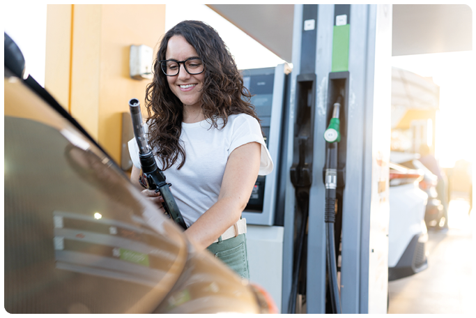 Woman smiling filling up car with fuel