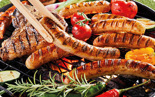 Mehrere gegrillte W rstchen, Steaks, Paprika, Tomaten und Kr uter liegen auf einem Grillrost ber gl hender Holzkohle.  Beschreibung von KI generiert