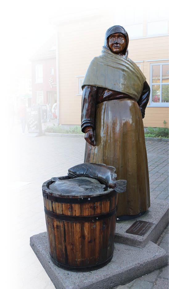 Eine lebensgro e Statue einer Person in traditioneller Kleidung steht neben einem gro en Holzfass mit einem Fisch darauf auf einem gepflasterten Platz vor einem Geb ude mit einem Schild, auf dem “Dolly Dimples" steht. Beschreibung von KI generiert