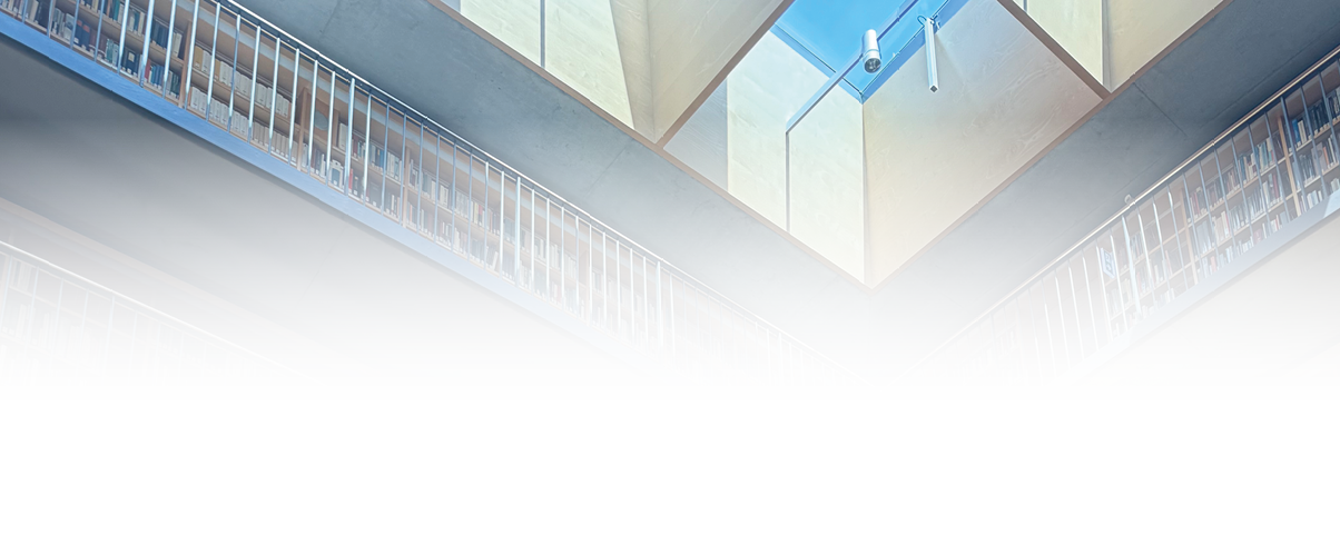 Eine hohe Bibliothekswand mit vielen B chern und mehreren Ebenen ist von St hlen und einigen sitzenden Personen umgeben, wobei Sonnenlicht durch ein Fenster auf den Holzboden f llt. Beschreibung von KI generiert