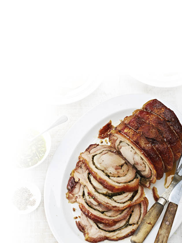 Auf einem wei en Teller liegt ein aufgeschnittener, gerollter Braten mit knuspriger Kruste, daneben liegen ein Messer und eine Gabel mit Holzgriffen. Beschreibung von KI generiert
