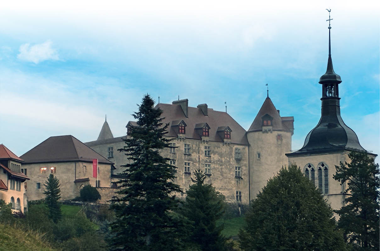 Eine historische Burg mit mehreren T rmen und einem hohen Kirchturm steht auf einem bewaldeten H gel unter einem bew lkten Himmel. Beschreibung von KI generiert