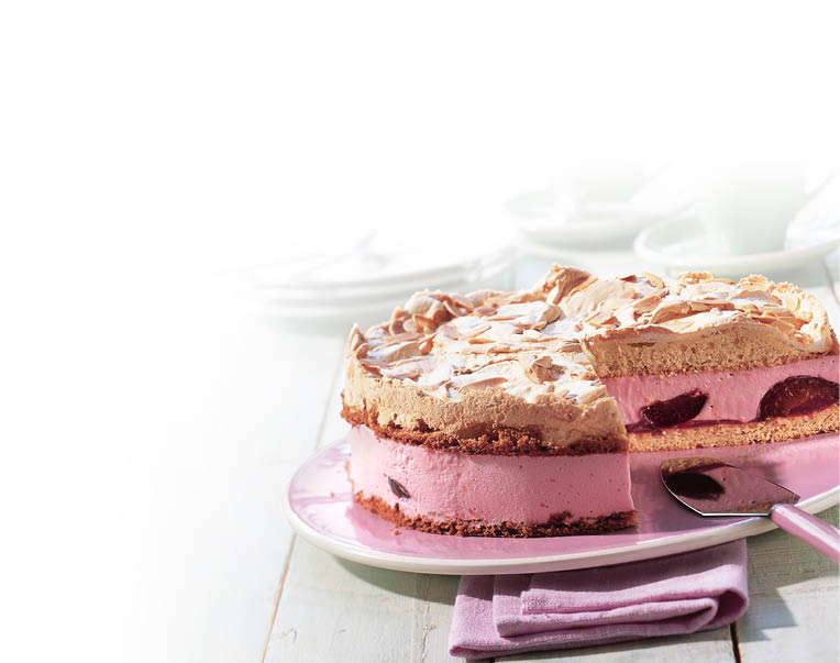 Eine Torte mit einer rosa F llung und Kirschen ist auf einem Teller mit einem Messer und einem lila Stoffserviette auf einem hellen Holztisch angerichtet. Beschreibung von KI generiert