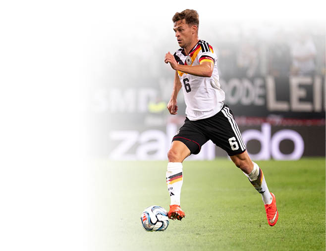 Eine Person in einem wei en Trikot mit der Nummer 6 und schwarzen Shorts l uft auf einem Fu ballfeld und kontrolliert den Ball mit dem Fu . Beschreibung von KI generiert
