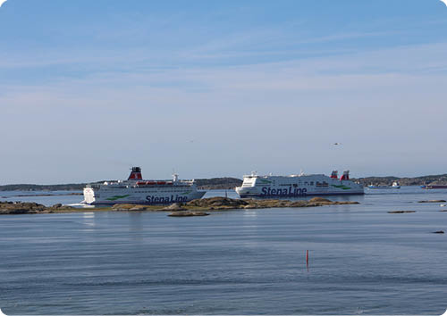 Zwei gro e F hren der Stena Line fahren auf ruhigem Wasser zwischen felsigen Inseln unter einem klaren blauen Himmel. Beschreibung von KI generiert
